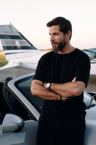 NOIRD men's black cotton t-shirt, side view next to car, 240g cotton jersey