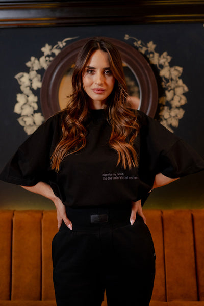 Women's NOIRD black cotton t-shirt, front view with black trousers